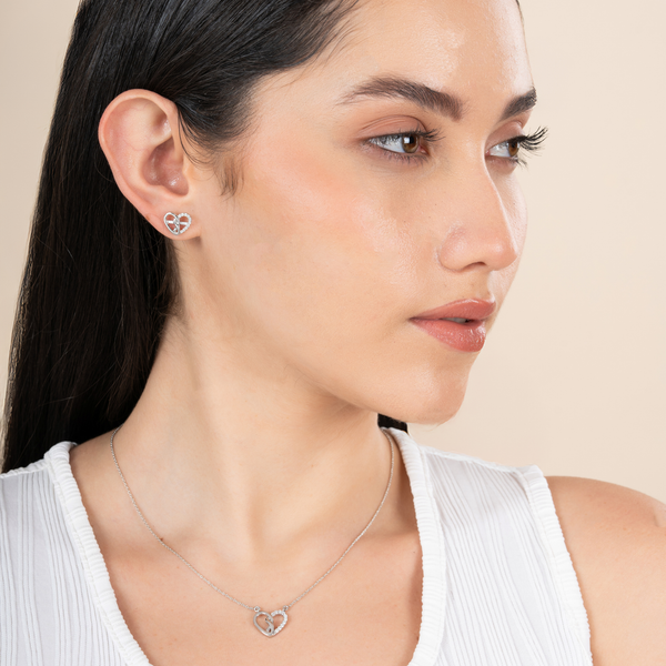 Woman wearing a heart-shaped earring and necklace on a beige background