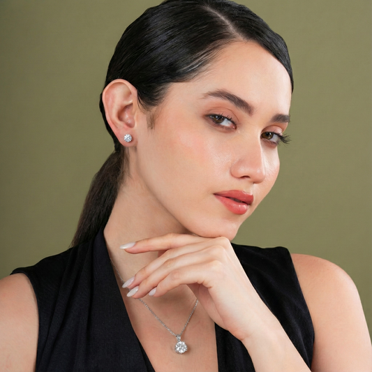 Woman wearing a necklace and earrings against a green background