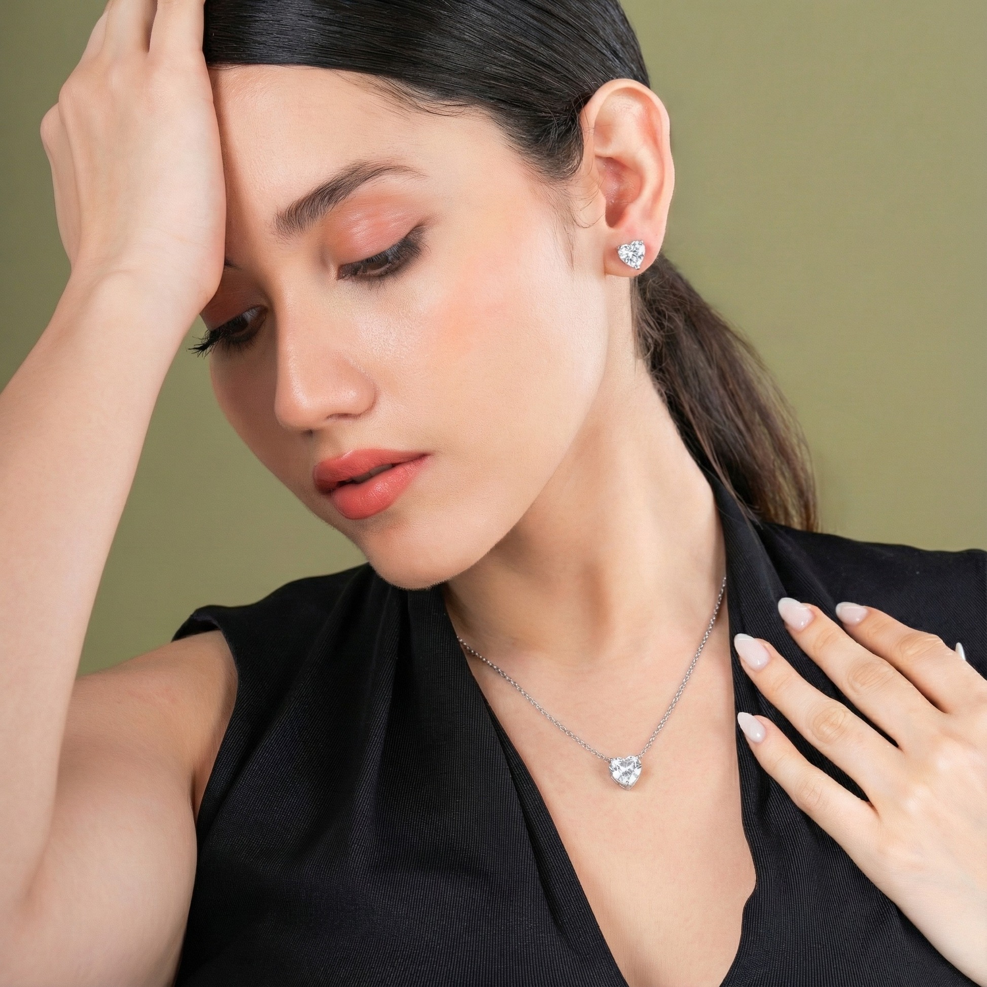 Woman wearing a necklace and earrings against a green background