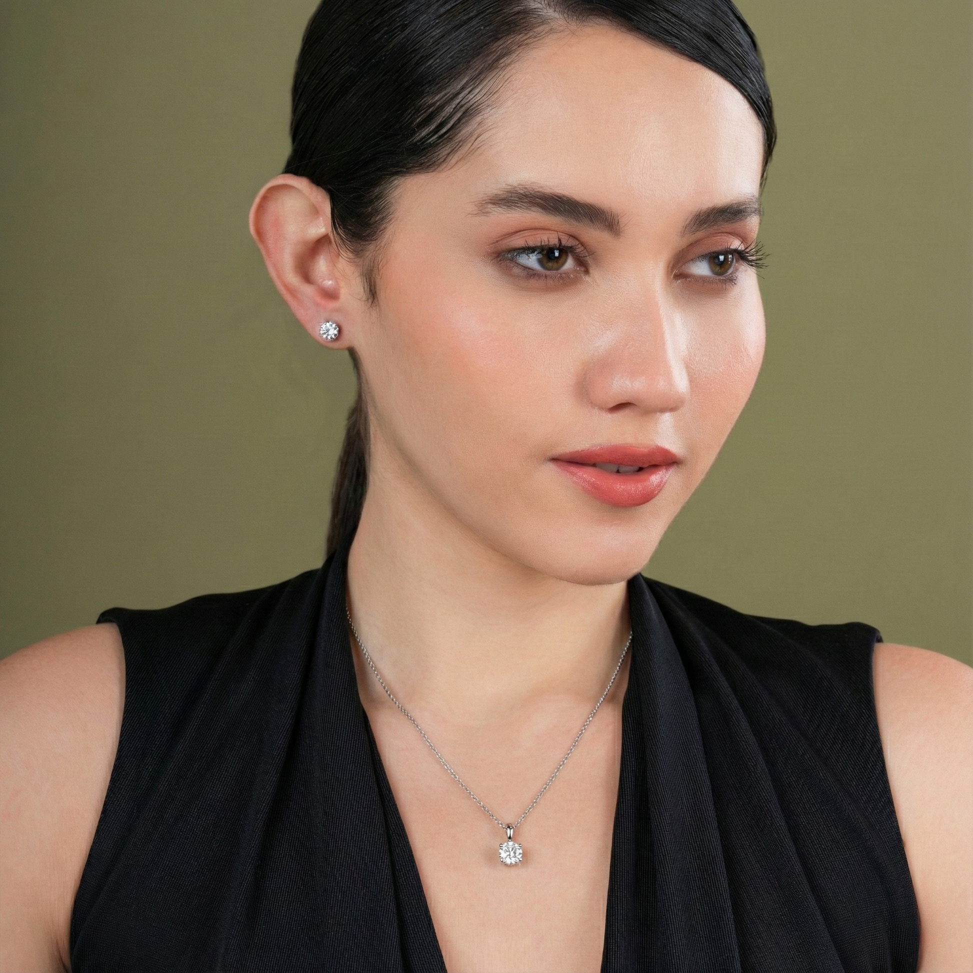 Woman wearing a necklace and earrings against a green background