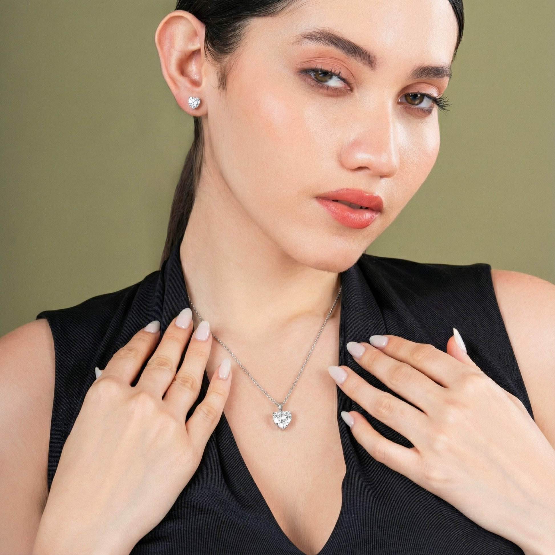 Woman wearing a necklace and earrings against a green background