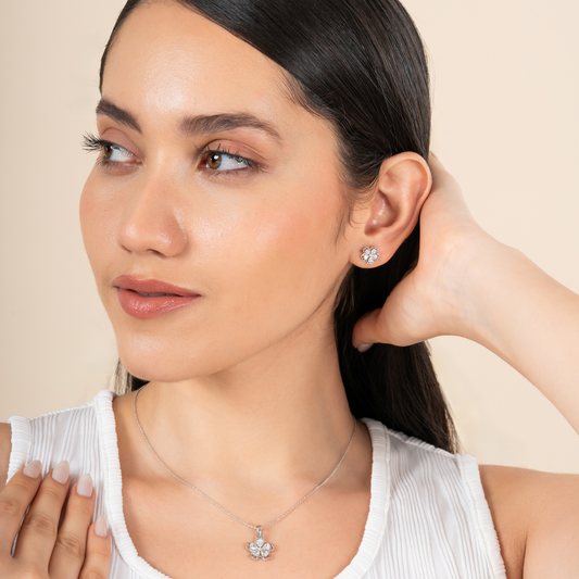 Woman wearing diamond earrings and necklace against a beige background
